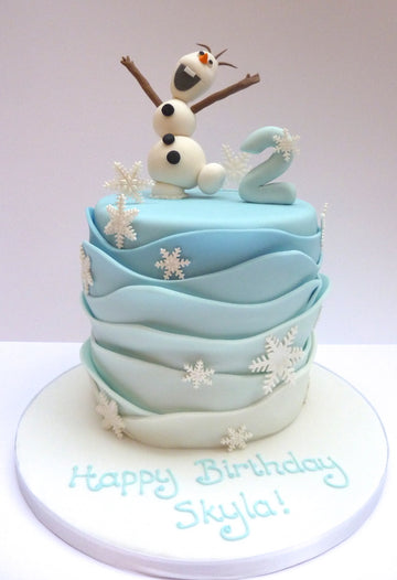 Olaf Birthday Cake delivered in London with sugar olaf on the top, snowflakes around the sides and waves of ombre pale blue icing around the sides