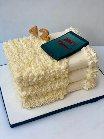 Cake decorated to look like a pile of towels with a tablet on top