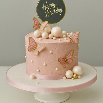 Pink birthday cake with butterflies and a 'Happy Birthday' topper on a gray background