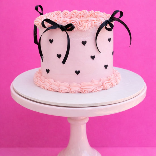 Pink lambeth birthday cake with black hearts and ribbon bows delivered in london