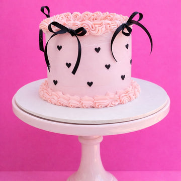 Pink lambeth birthday cake with black hearts and ribbon bows delivered in london