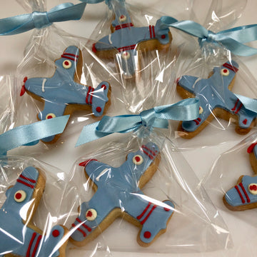 Plane-shaped cookies with blue ribbons in clear packaging on a white background