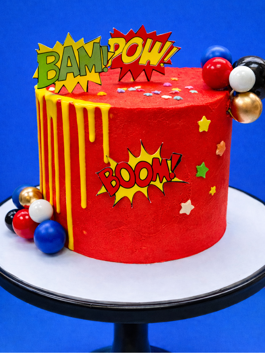 red super hero kids birthday cake with comic book exclamations to decorate delivered in london