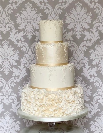 4 tier wedding cake with a ruffle bottom tier, daisies and blossoms falling down the cake on the other tiers delivered across london