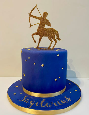 Blue cake with gold accents and a Sagittarius zodiac sign figure on top.