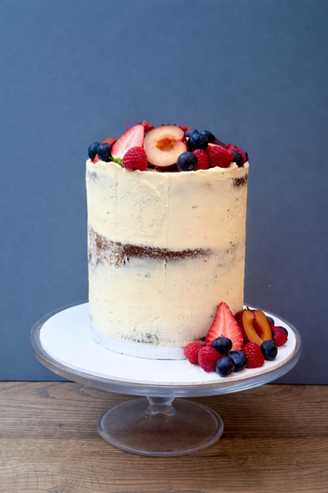 semi naked tall buttercream cake decorated with berries and fruit delivered in london