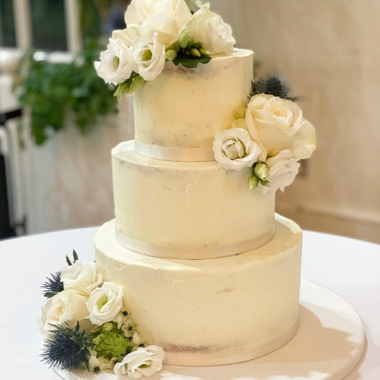 Semi naked wedding cake with fresh white flowers delivered in london