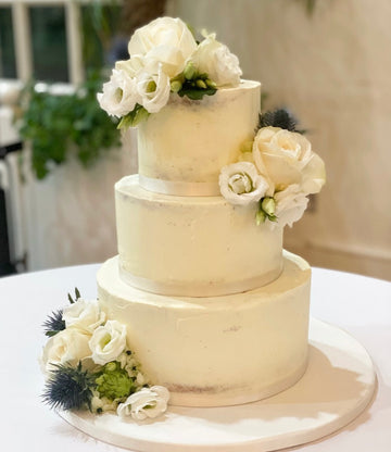 Semi naked wedding cake with fresh white flowers delivered in london