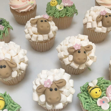 Cupcakes decorated to look like sheep and grass with bees