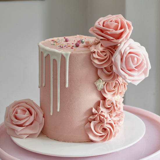 Cake decorated with buttercream roses, silk roses and a chocolate drip