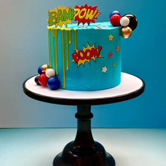 super hero birthday cake delivered in london with comic themed exclamation speech bubbles to decorate