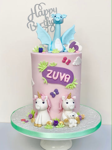 Unicorn twins at the bottom of a tall pink cake with a blue dragon on top