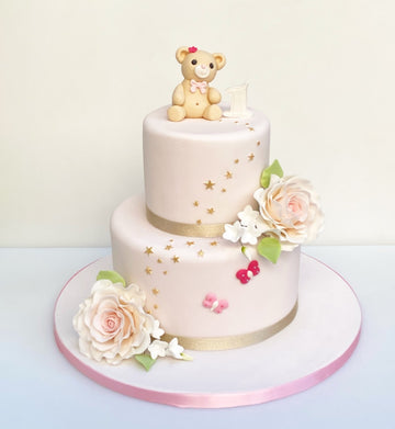2 tiered christening cake decorated with a girl teddy and sugar roses, blossoms and stars