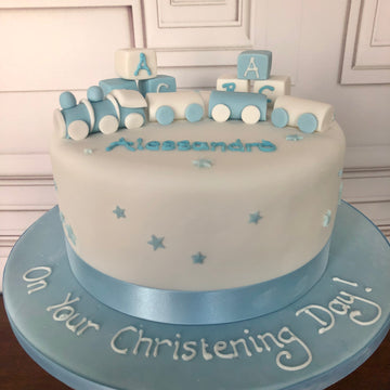 White cake with toy train and blocks on the top