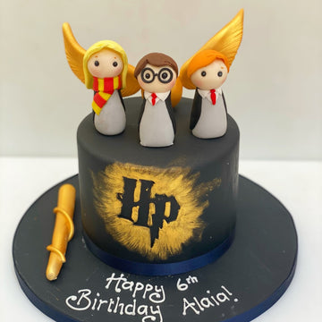 harry potter birthday cake featuring harry potter, hermione and Ron made from sugar and a snitch in the background