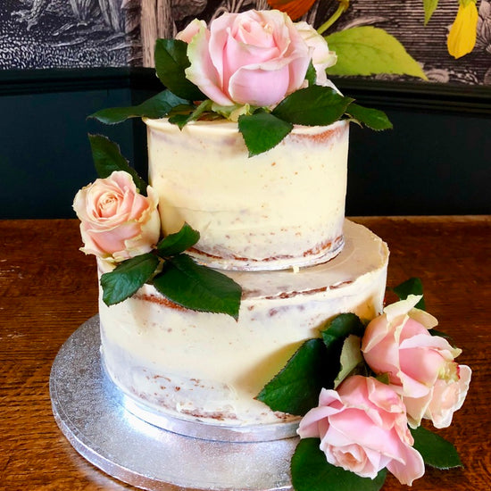 semi naked wedding cake on two tiers with fresh flowers delivered in london