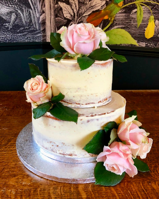 semi naked wedding cake on two tiers with fresh flowers delivered in london