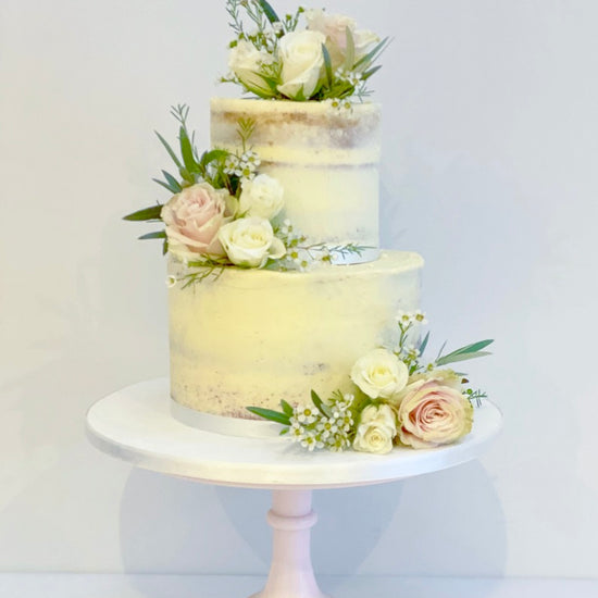 semi naked wedding cake on two tiers with fresh flowers delivered to london