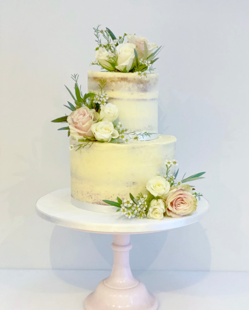semi naked wedding cake on two tiers with fresh flowers delivered to london