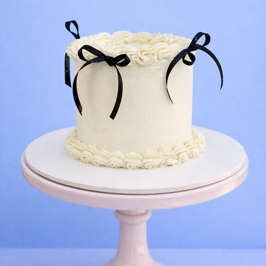 white buttercream cake with vintage lambeth piping and black ribbons delivered in london